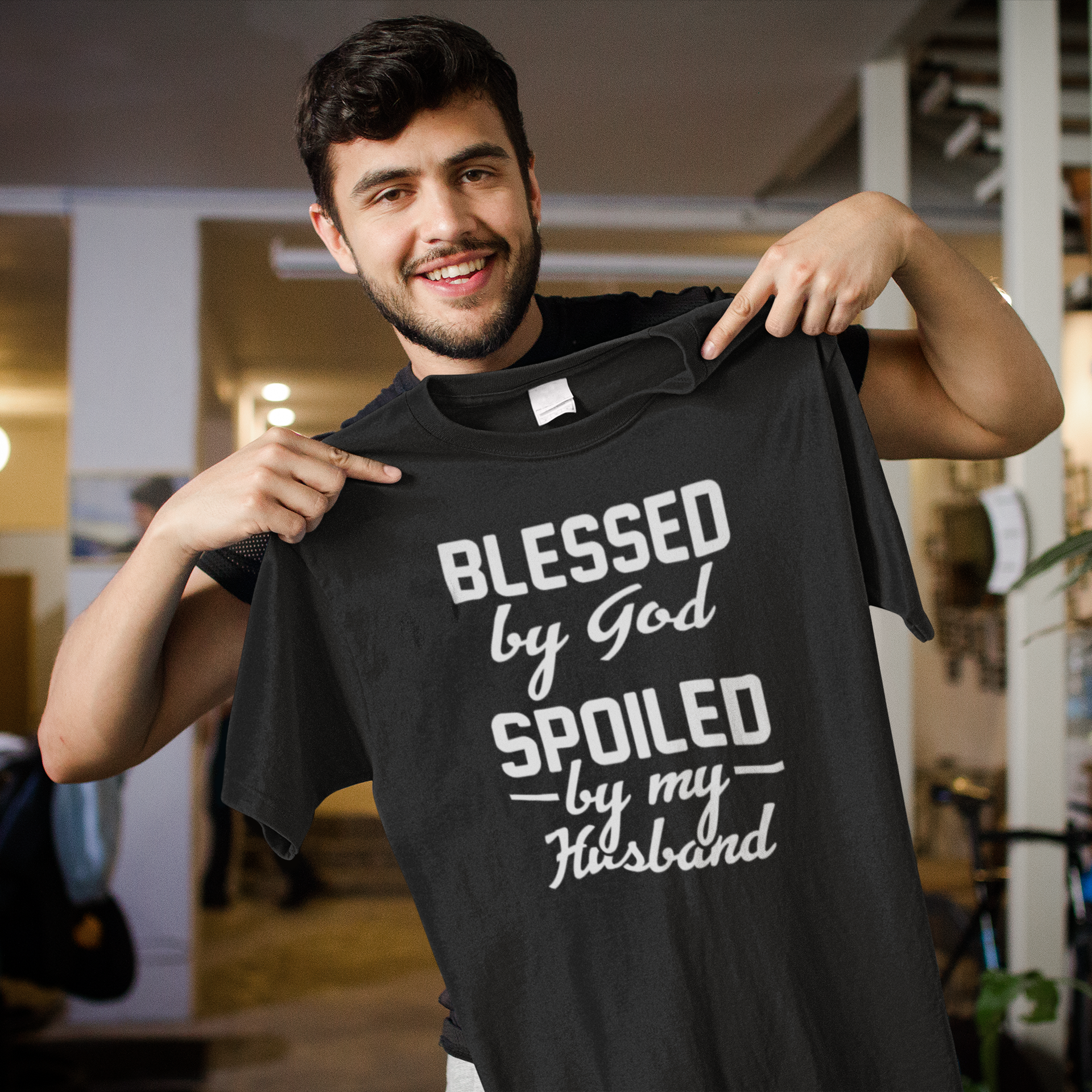 Black heavyweight garment-dyed cotton tee with "Blessed by God, Spoiled by My Husband" text design, made from 100% USA cotton.