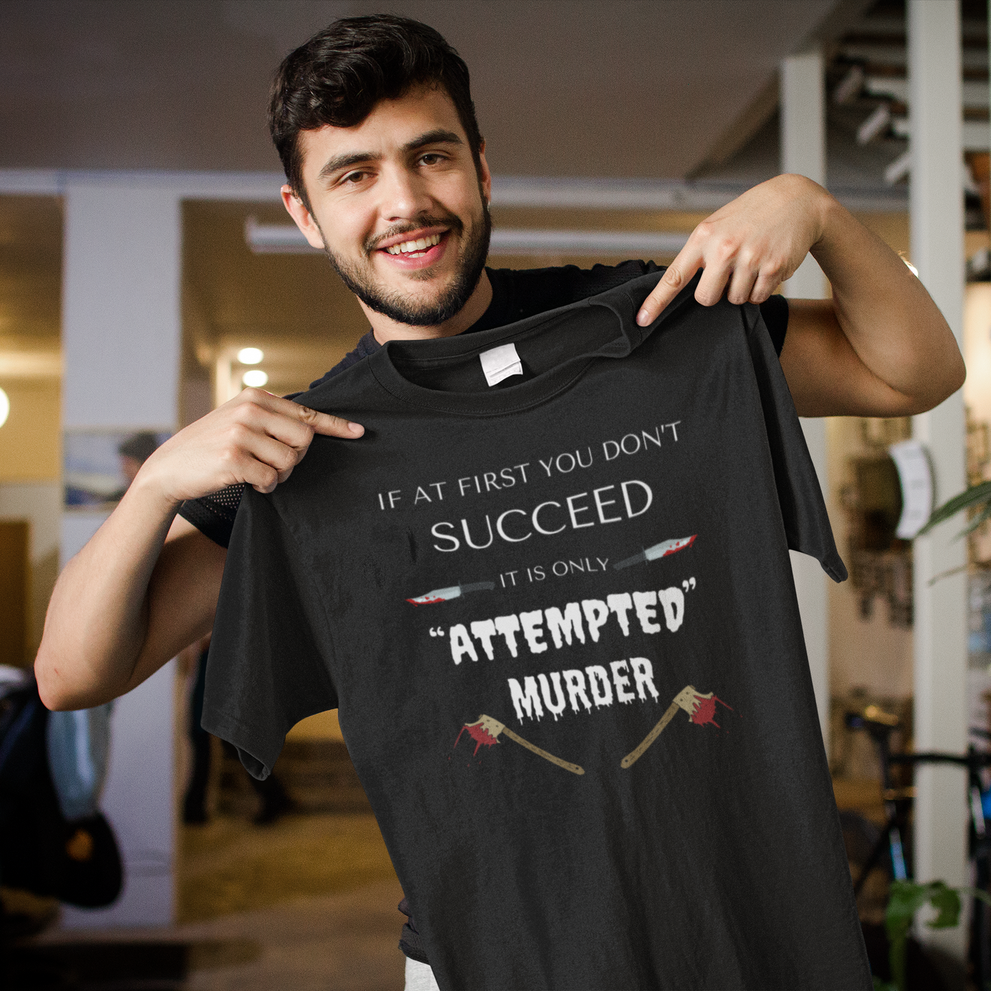 Black heavyweight garment-dyed cotton t-shirt featuring humorous quote 'If at first you don't succeed, it is only attempted murder' with images of bloody knives and axes